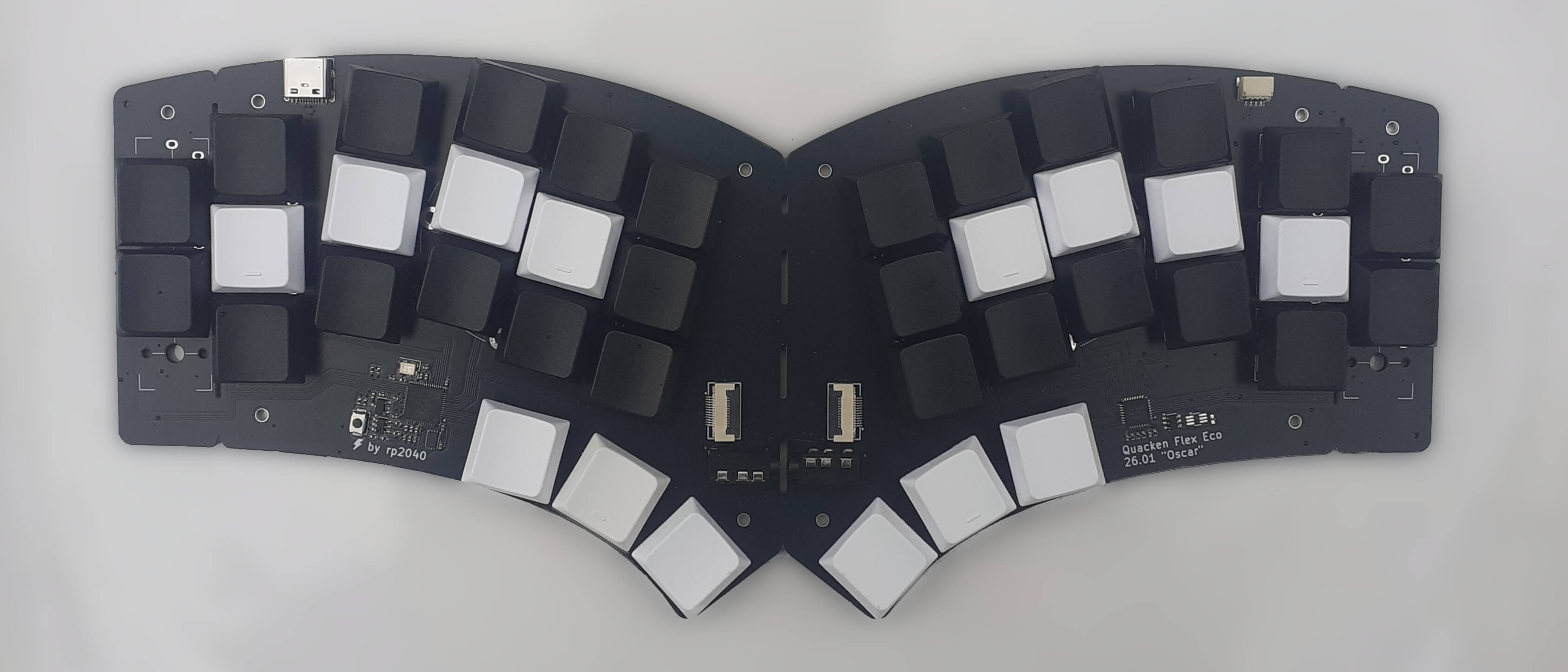 a unibody Quacken keyboard seen from above: 40 keys, white keycaps on home and thumb keys, black keycaps on all other keys