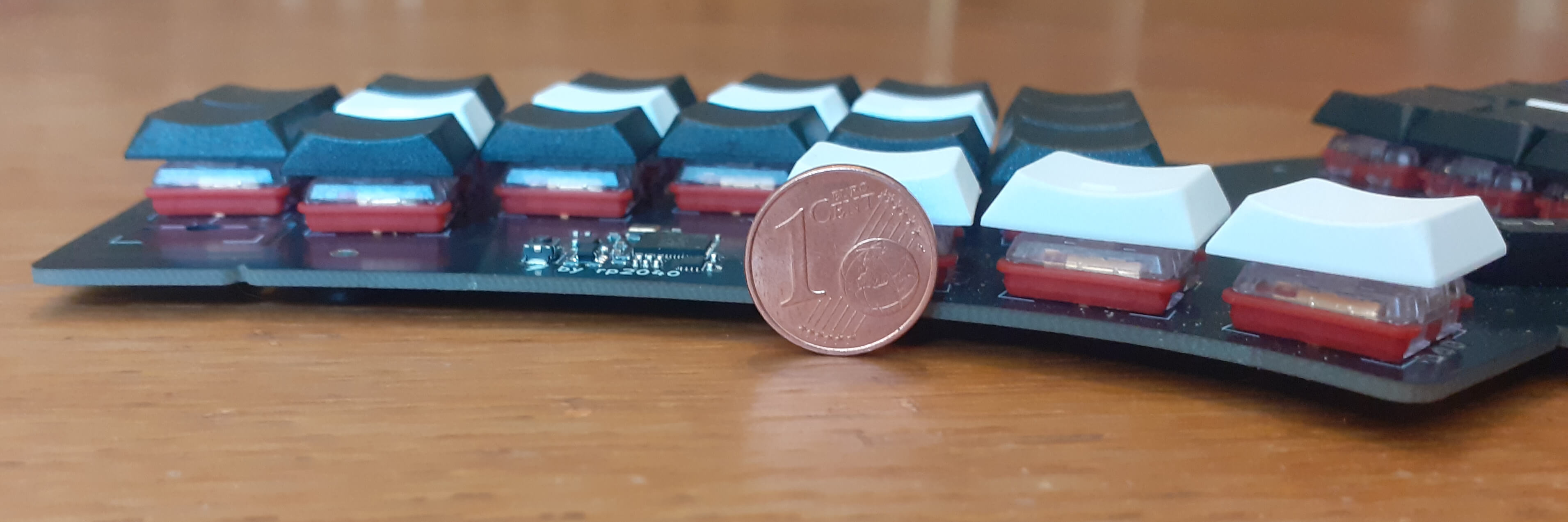 a unibody Quacken keyboard seen from the side, with a 1¢ coin for scale