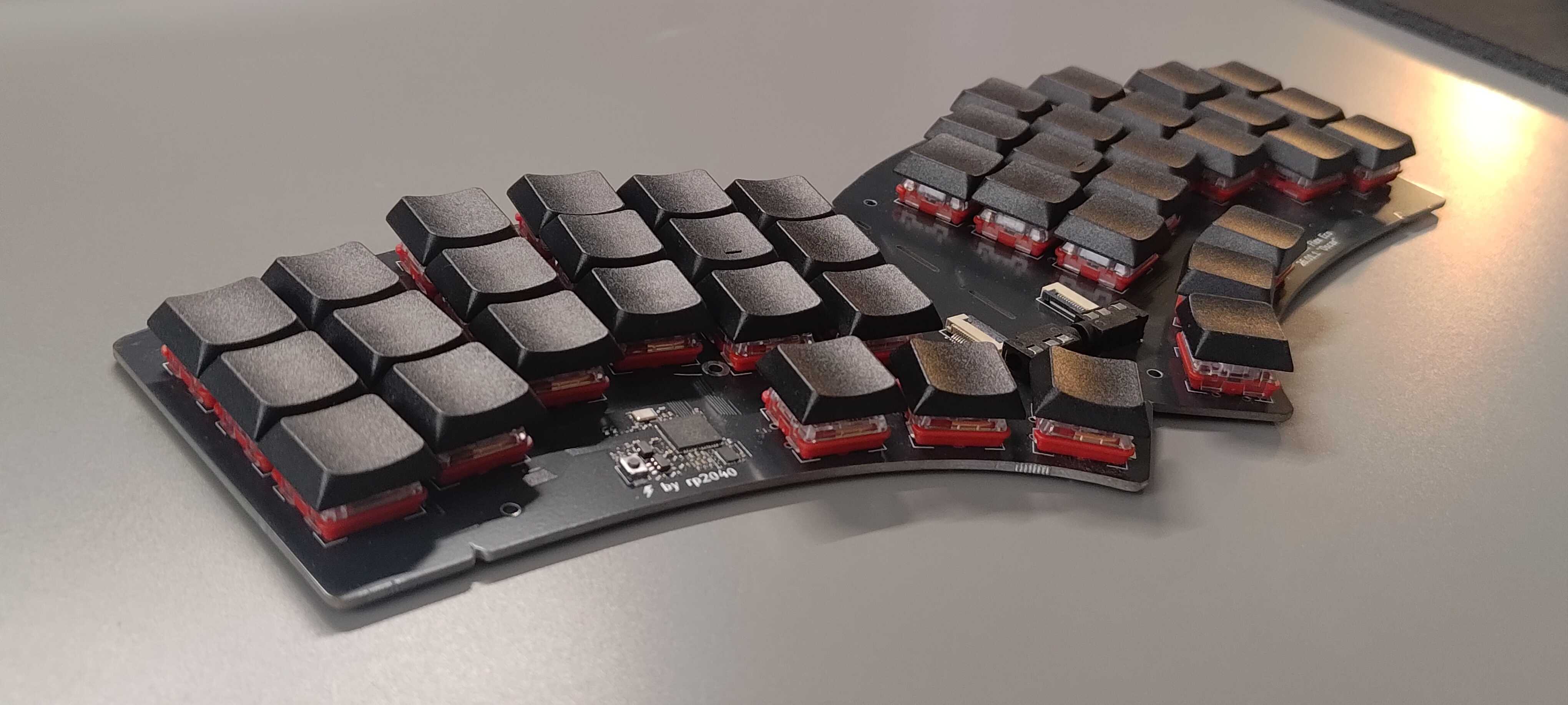 a Quacken keyboard on a table: unibody, 42 keys, red switches, black keycaps